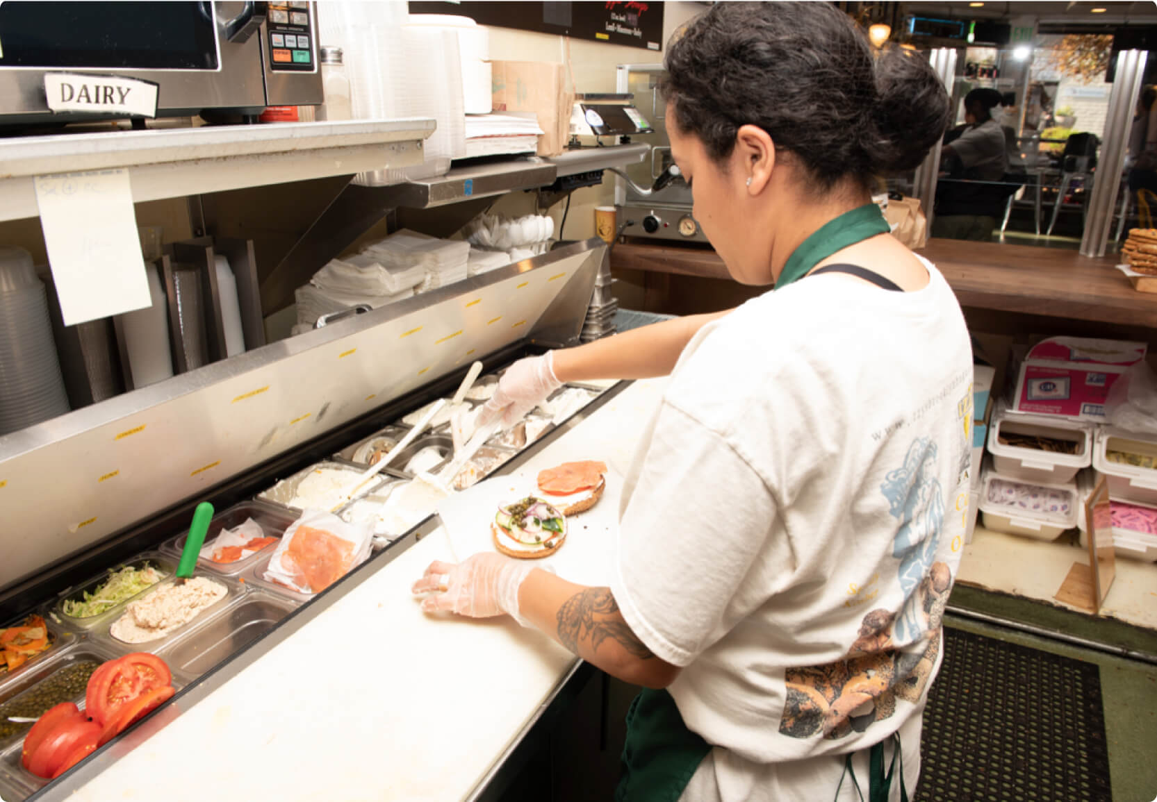 Hourly customer Izzy's Brooklyn Bagels worker while preparing a sandwich