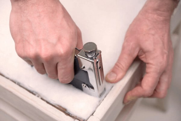 Hands stapling material to frame