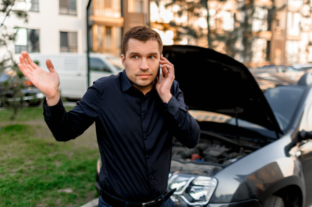 Car breakdown concept. the car will not start. a young man is calling for a car service. they cannot fix the car on their own. insurance must cover all costs. Premium Photo