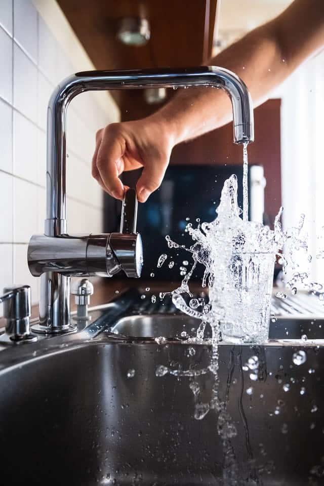 pouring glass of water from a faucet