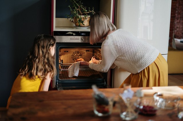 mom and daughter using oven
