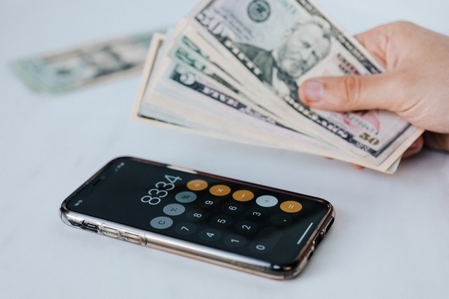 hand holding money with phone calculator