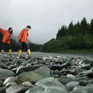 Couple walking across rocks of river bank.
