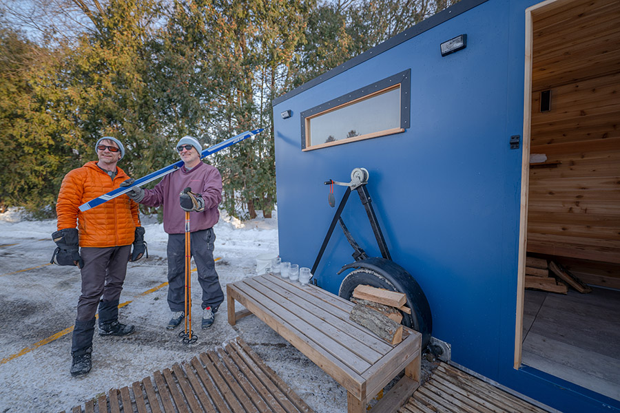 Two people standing outside of a mobile sauna