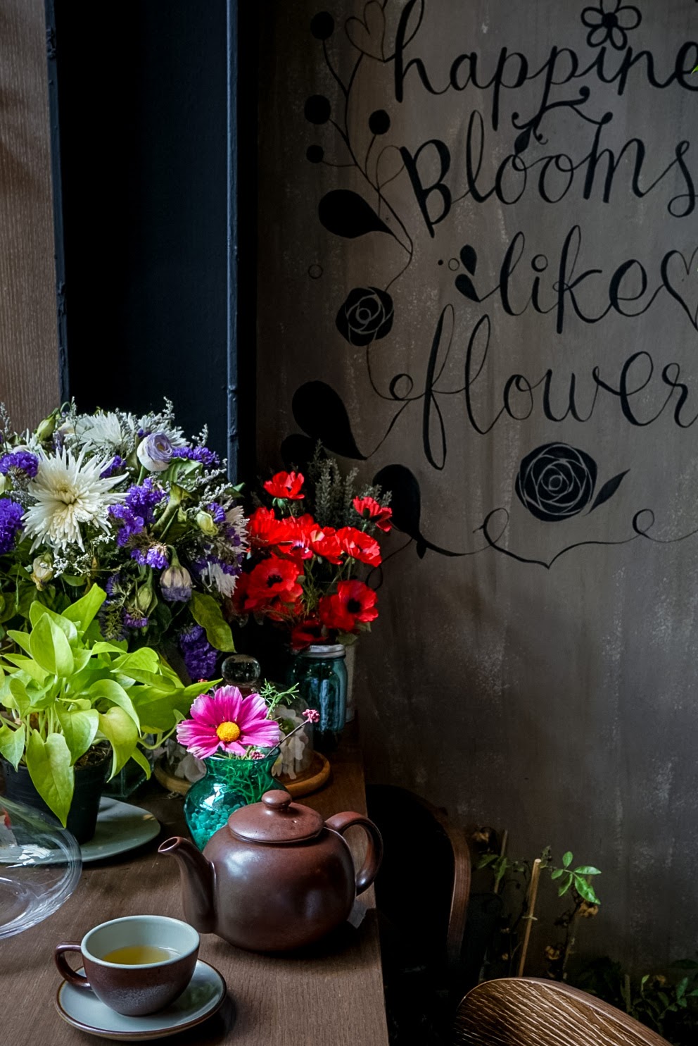 Vitrine da loja de flores e citação de felicidade na parede.