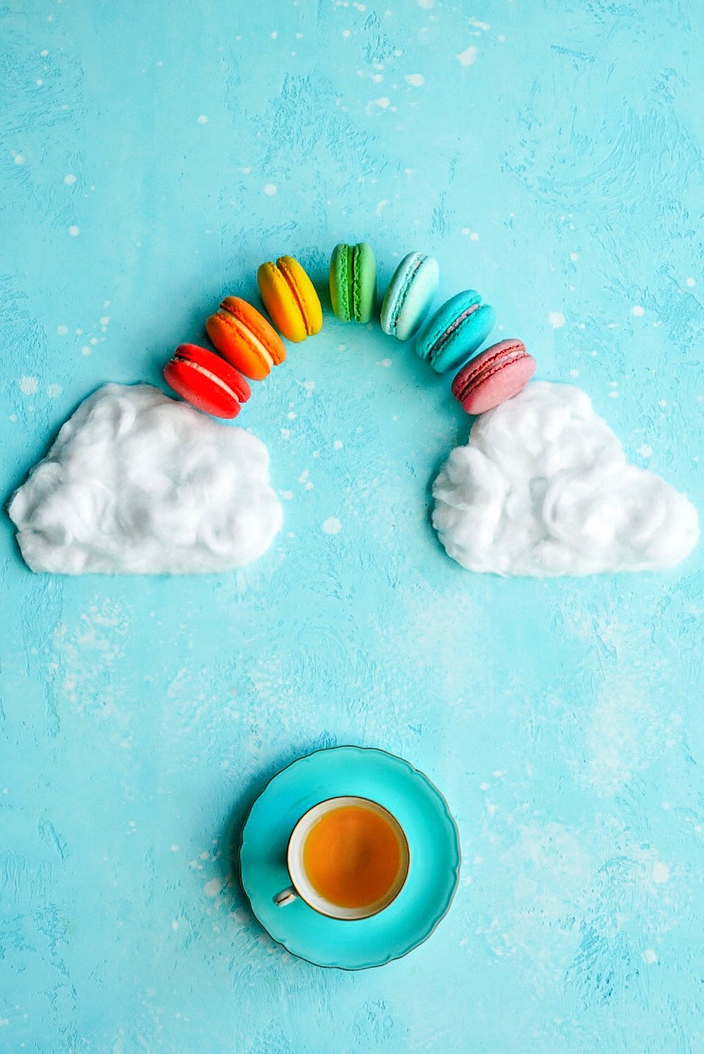 Flatlay alegre de um arco-íris feito de macarons e uma xícara de chá