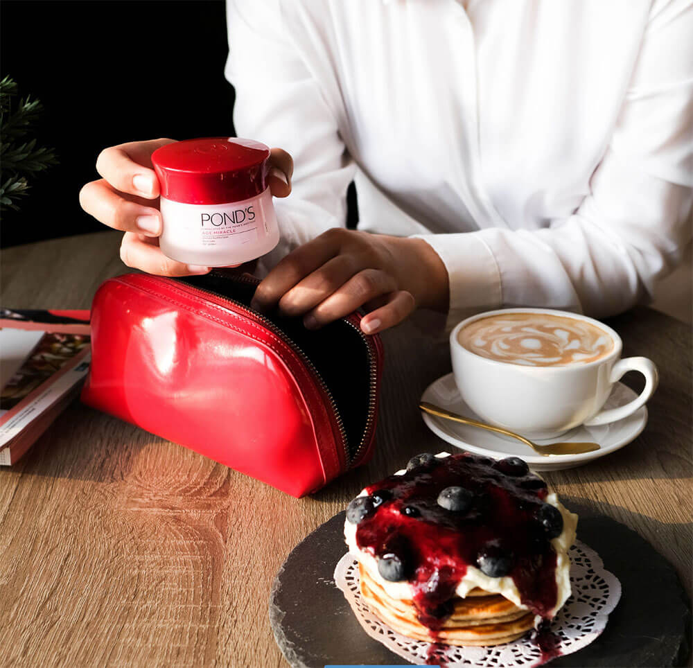 Produtos de beleza em estojo de maquiagem em cafeteria com café e panquecas
