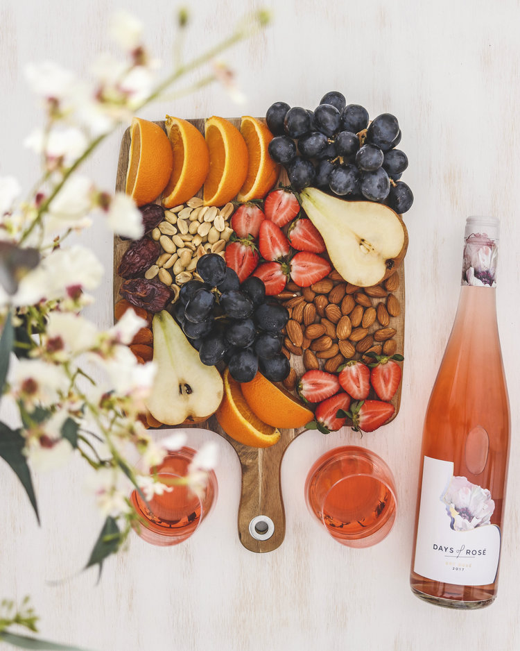 Prato de frutas frescas e nozes servido com vinho rosé