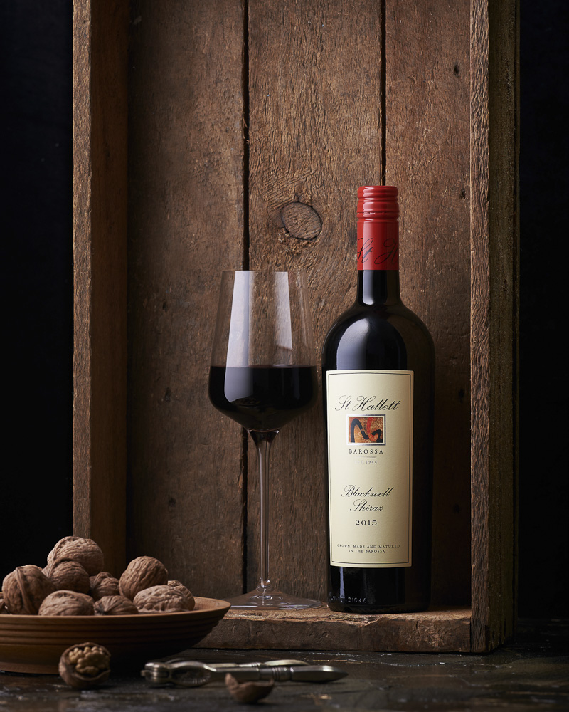 Garrafa de vinho e taça de vinho tinto com nozes em uma caixa de madeira