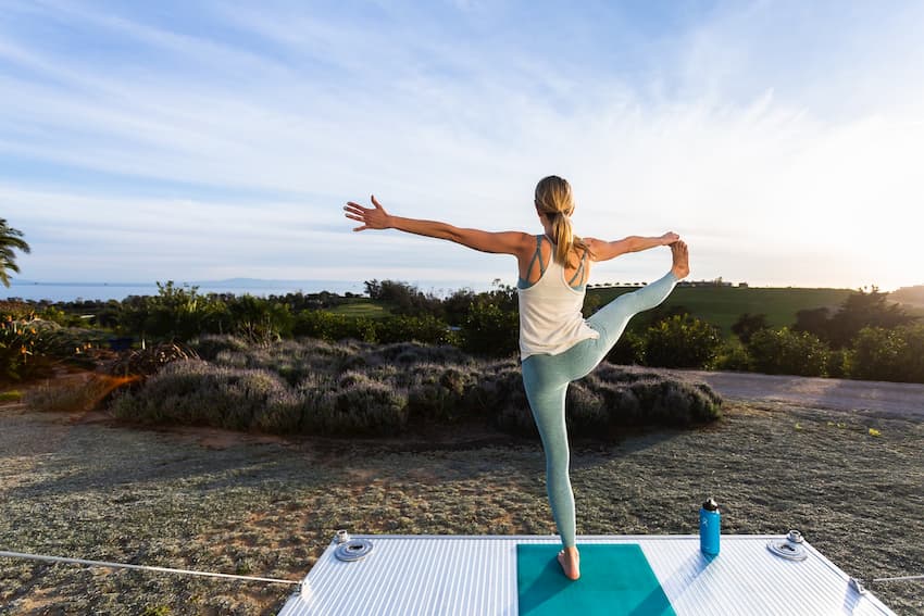 Woman doing yoga on the deck of a luxury travel trailer