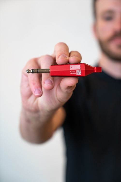 Gimme Co-Founder, Evan Jarecki, holding the Gimme Key Pro wireless Bluetooth DEX adapter for vending machines and direct store delivery (DSD) route drivers. Available in Gimme RED or Combat BLACK.
