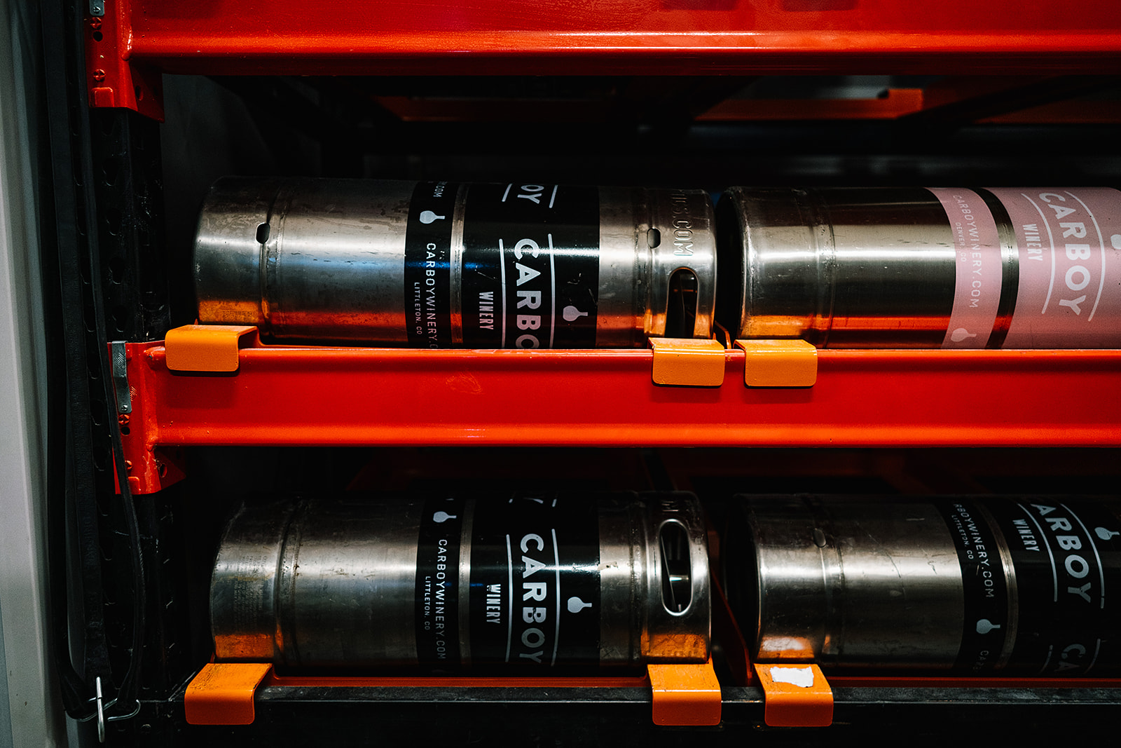 Carboy Winery wine kegs stacked on a red shelf.