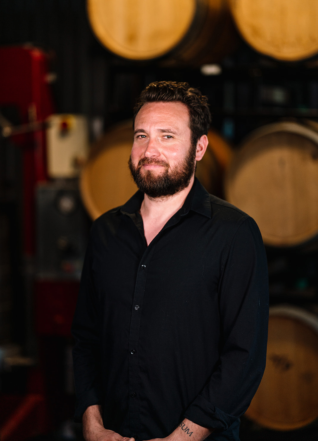 Carboy Head Winemaker, Tyzok Wharton, standing in front of wine barrels