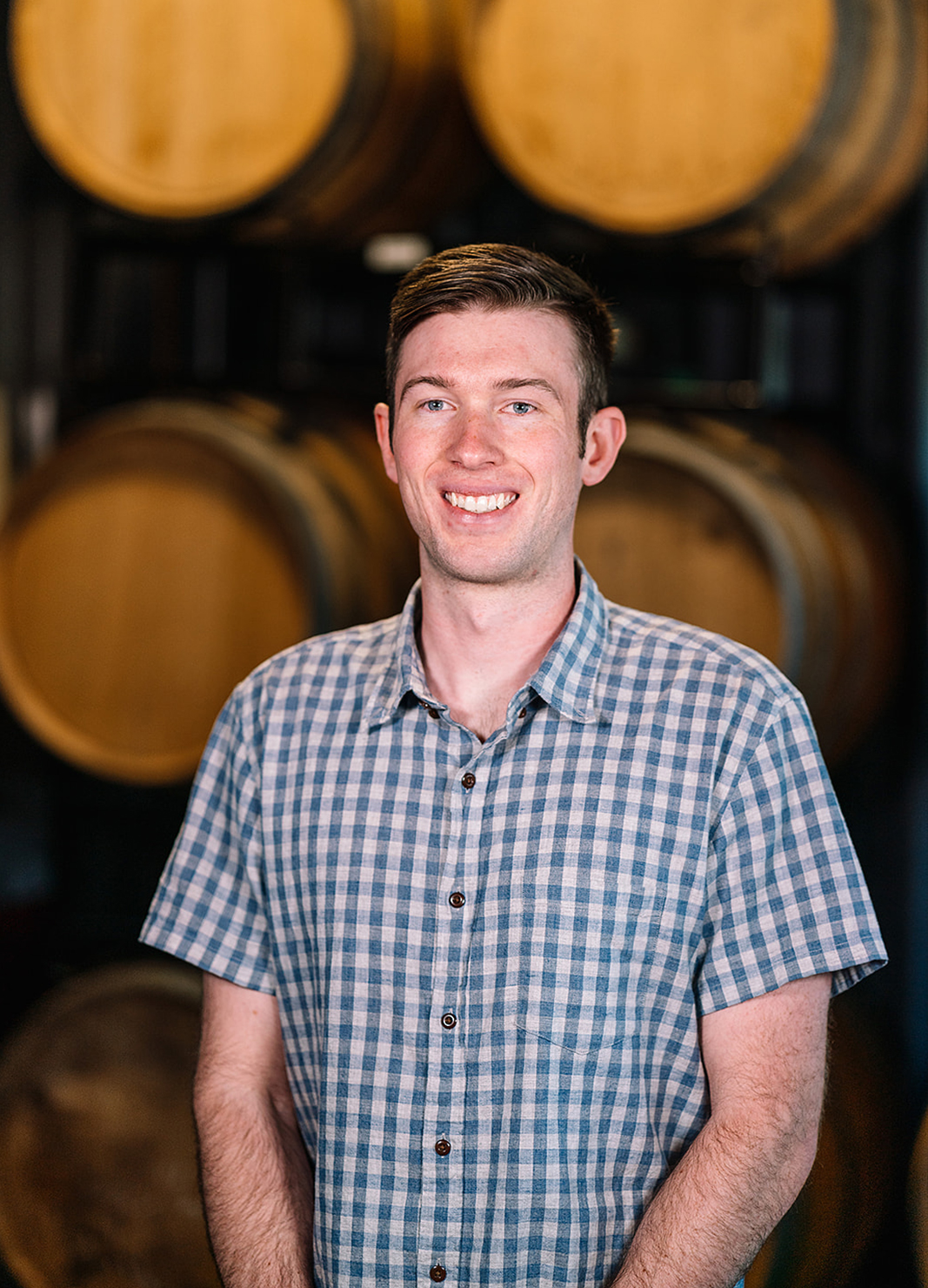 Carboy Production Specialist, Nic Carter, standing in front of wine barrels