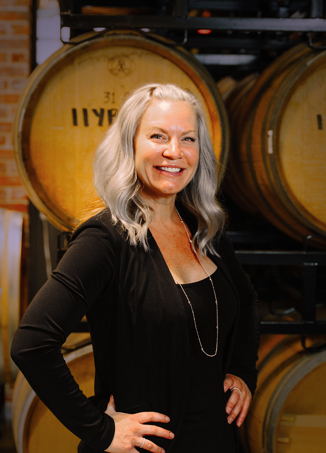 Carboy Tasting Room Manager, Cindy Davis, standing in front of wine barrels