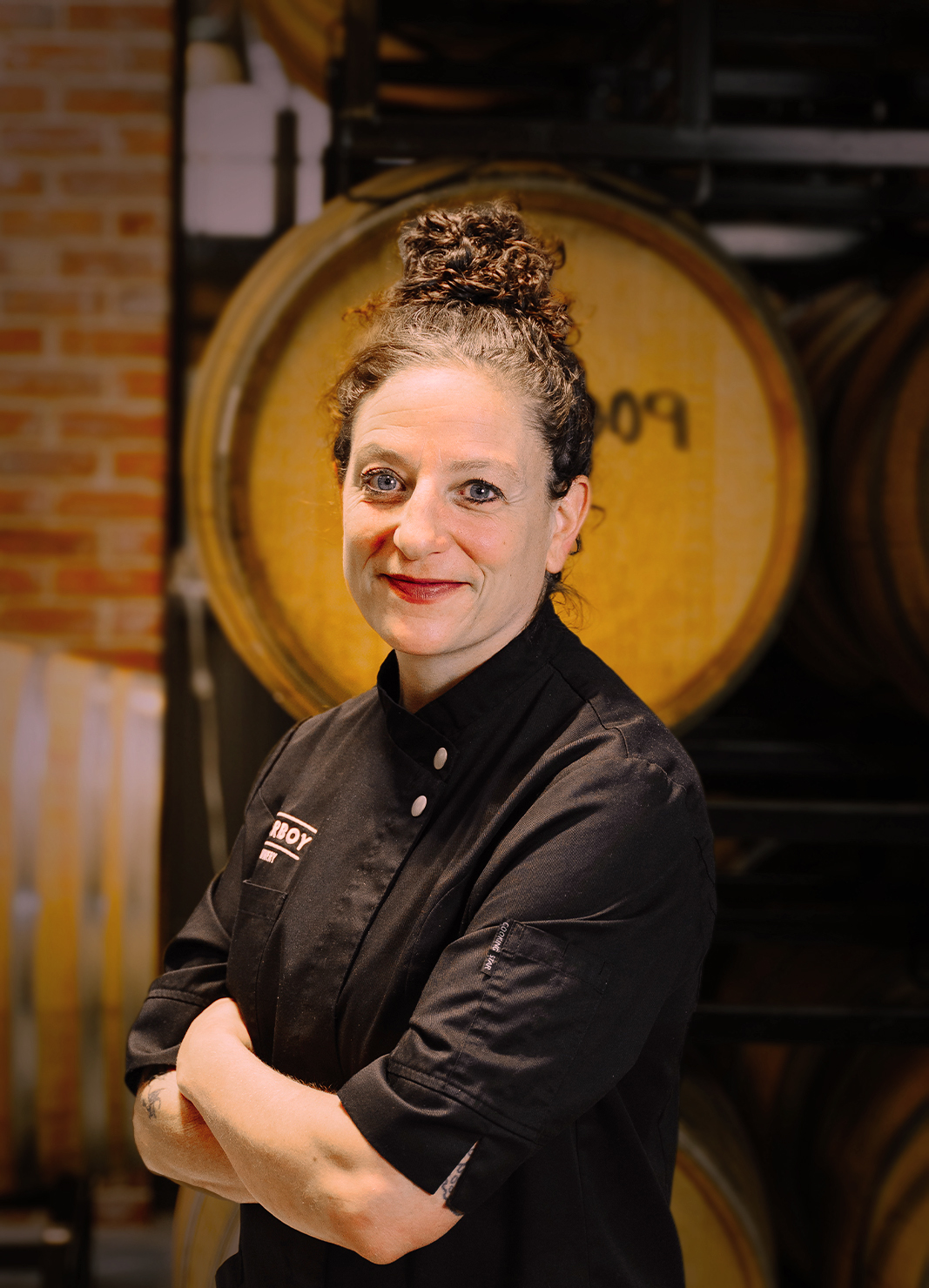 Carboy Executive Chef, Rebecca Weitzman, standing in front of wine barrels
