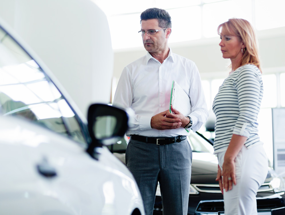Car salesmen with customer looking at used cars