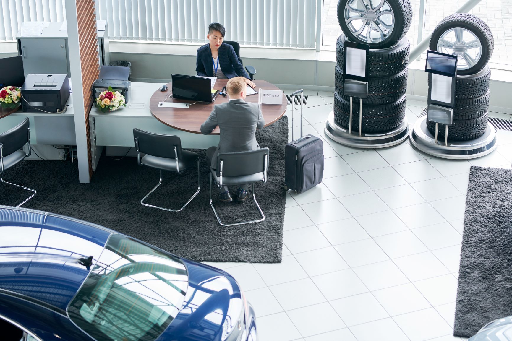 man at desk with female car salesperson at dealership