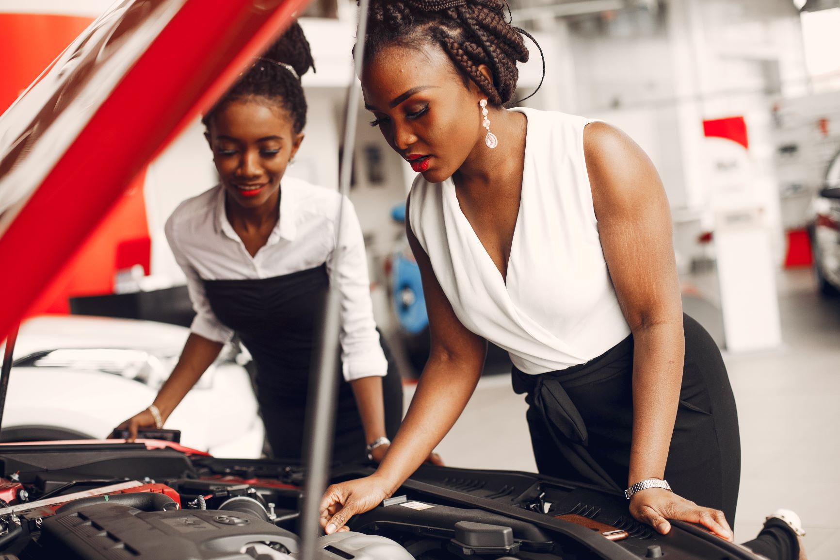 two women looking at a car engine