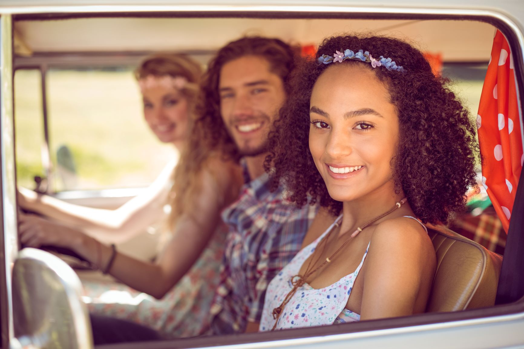 three young people sitting in front of car