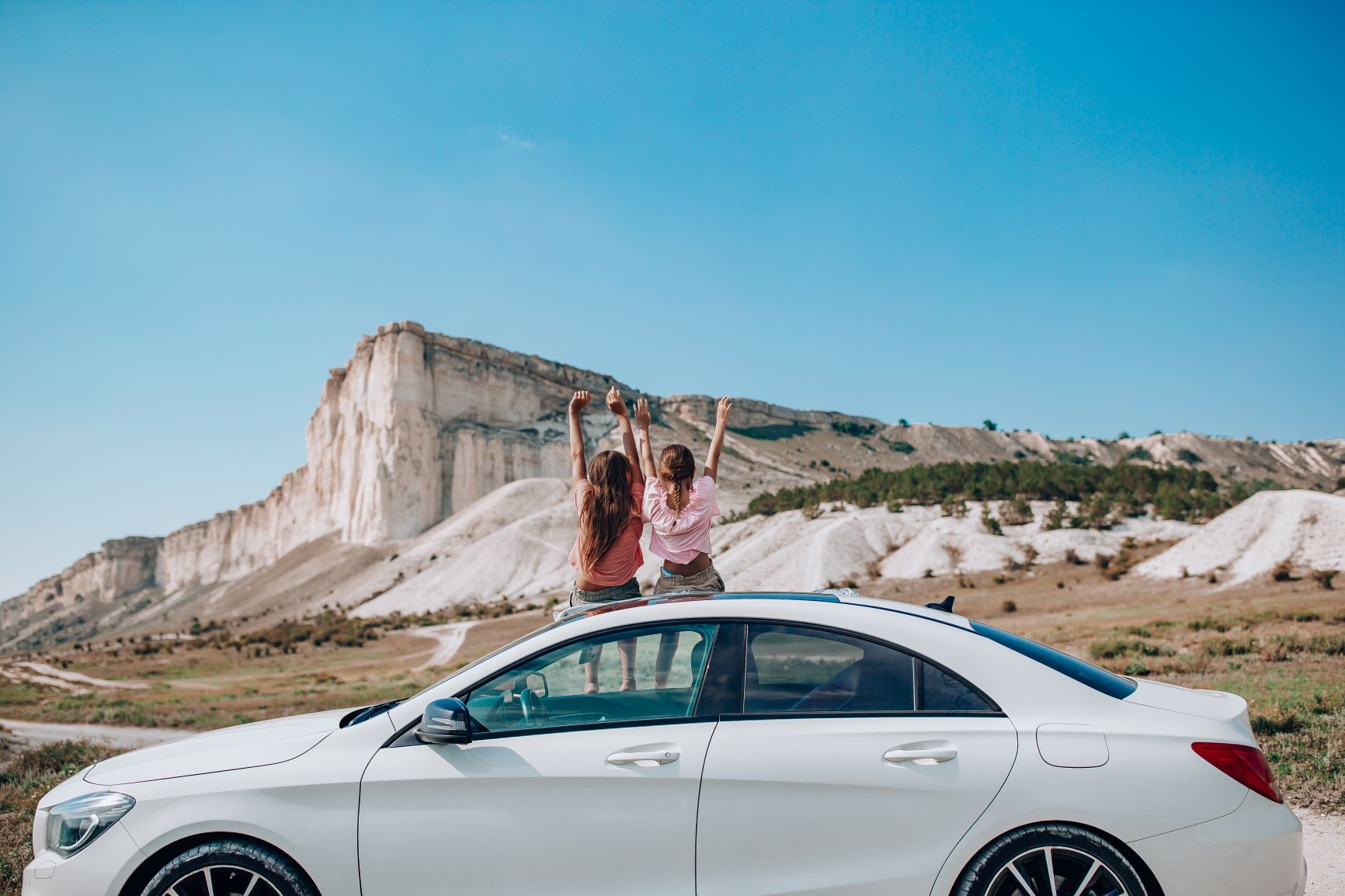 two girls sitting on top of car