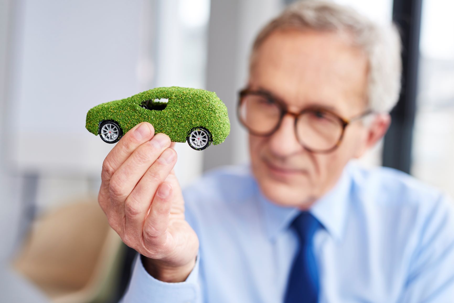 man holding up green eco friendly car