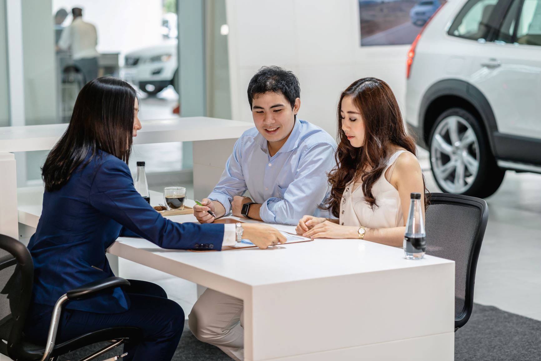 couple signing a contract at a car dealership