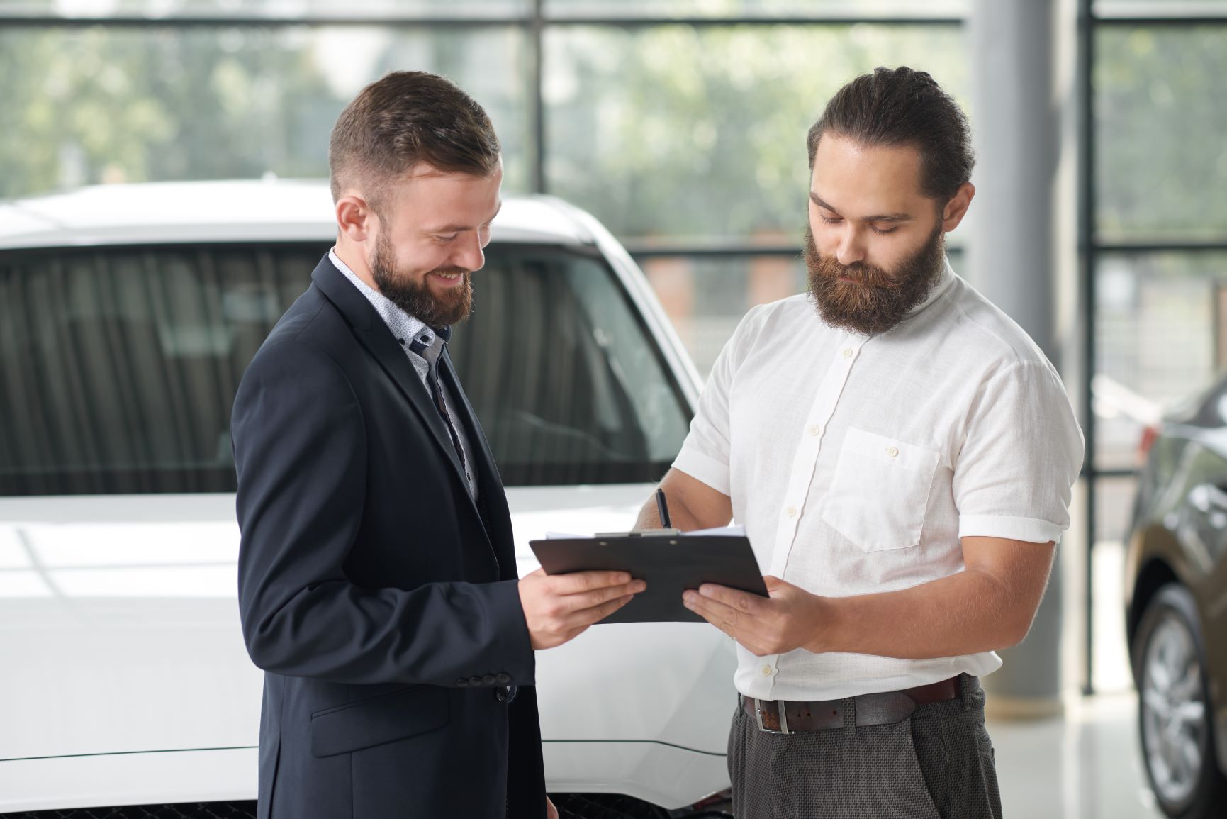 man signing car contract in a dealership