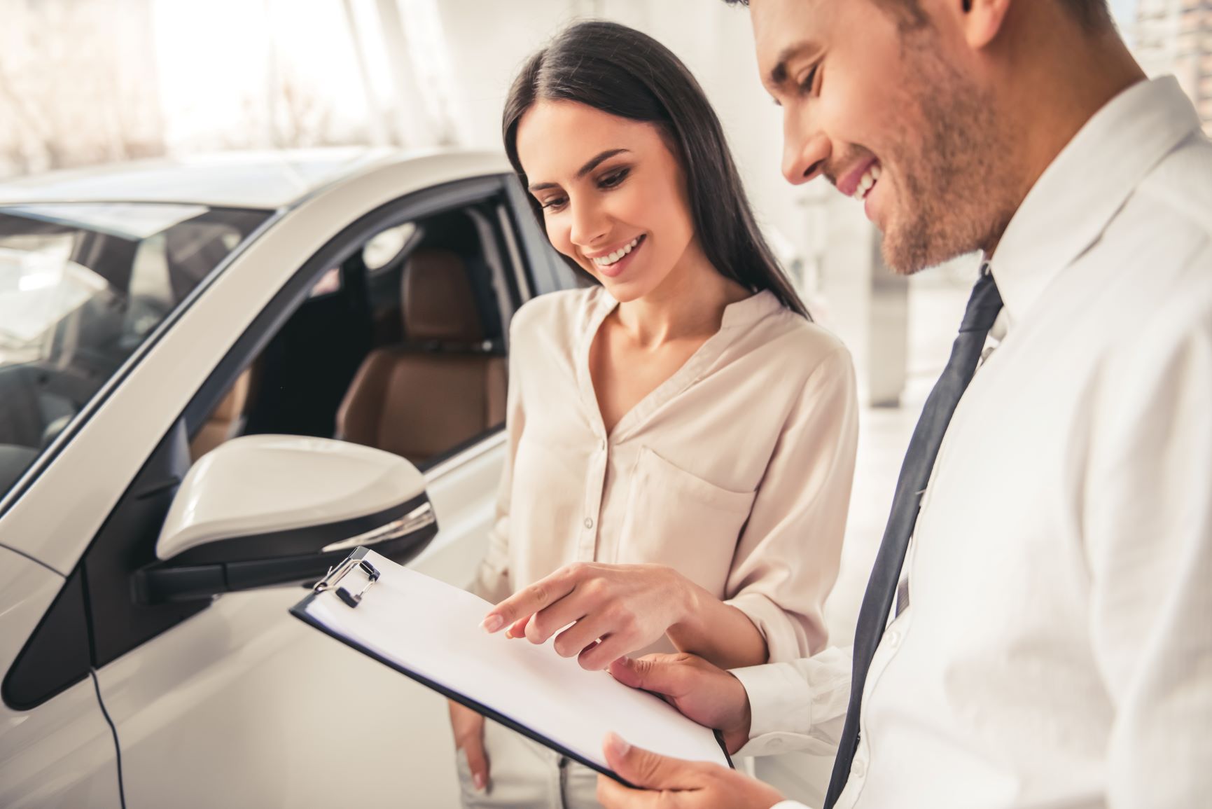 woman and car salesman signing paper