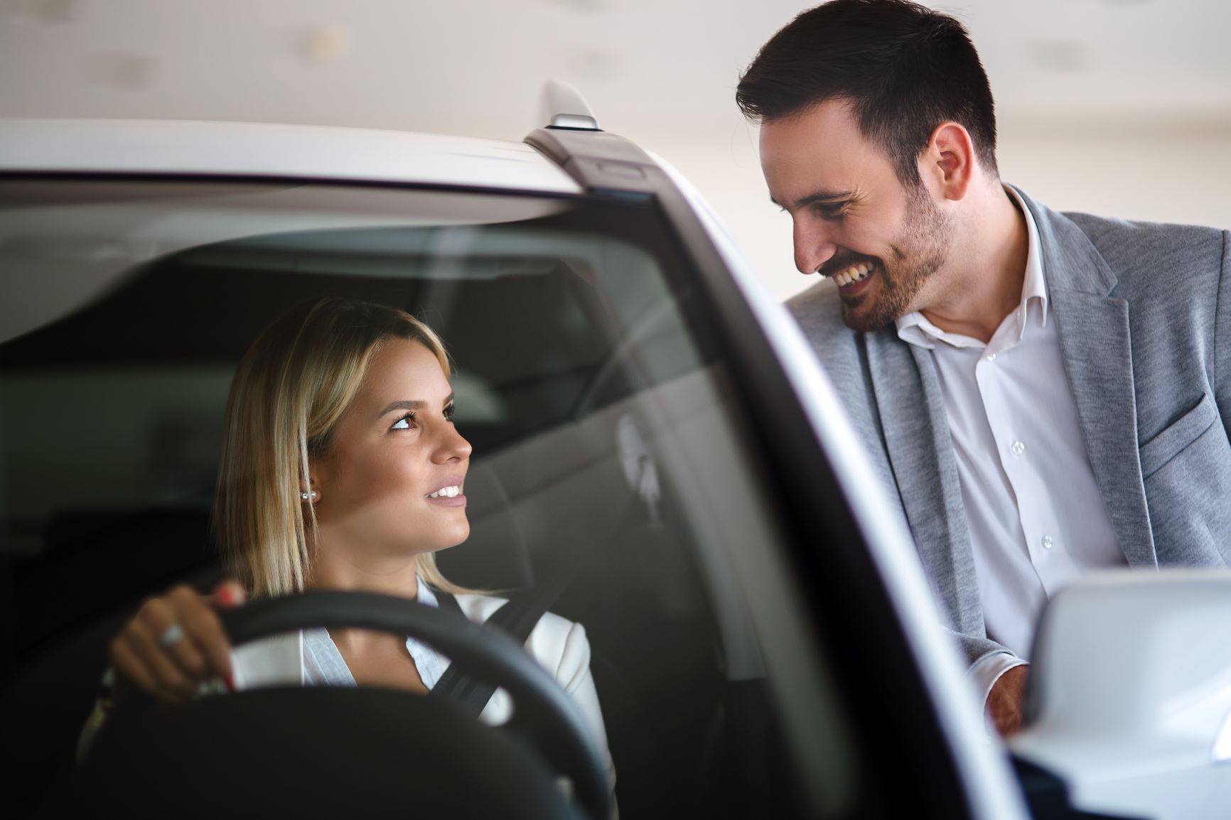 car salesman talking to blonde woman in car