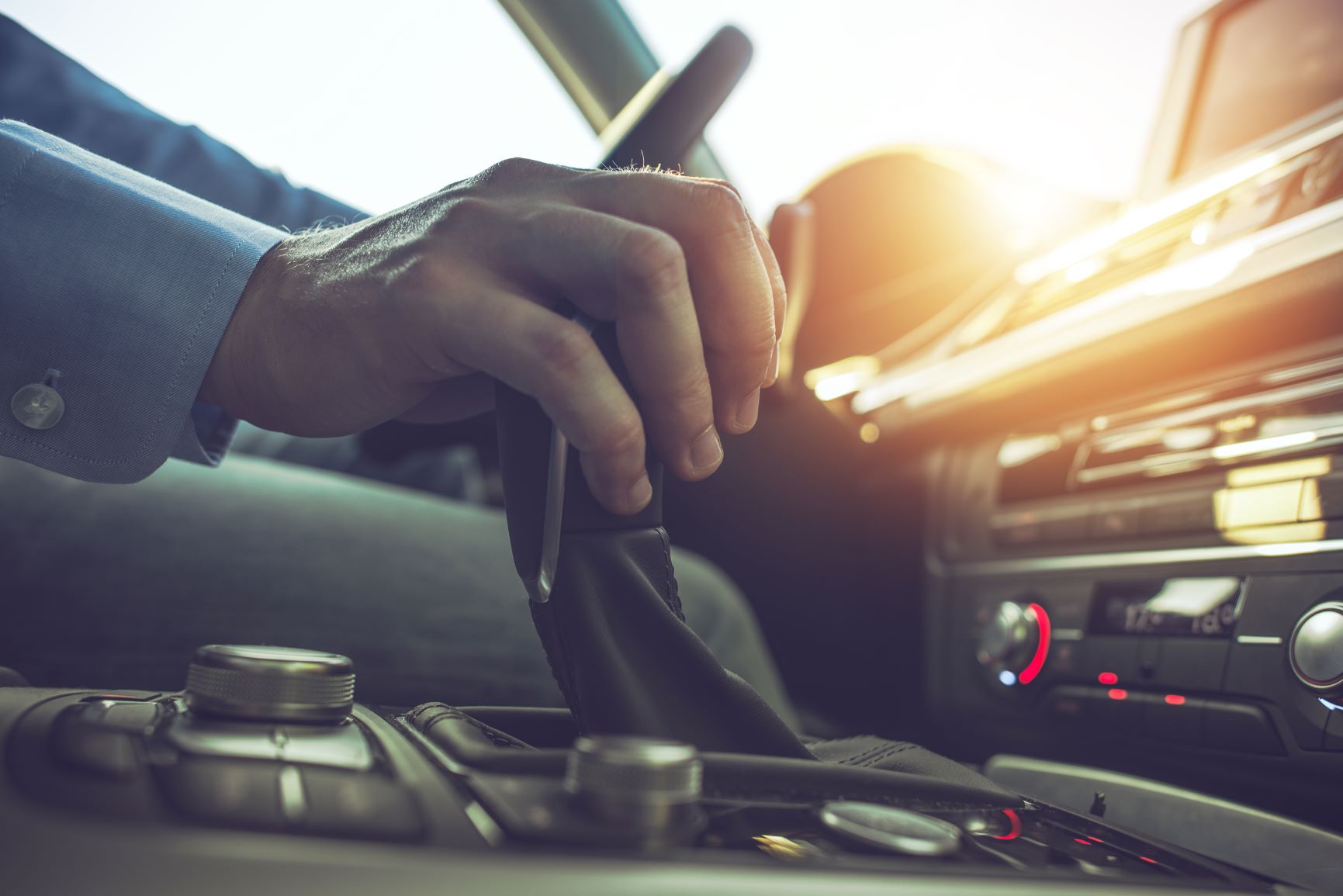 hand on shifter driving a car at sunset