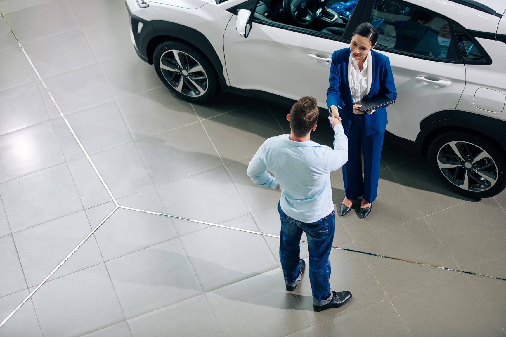 female car salesperson talking to man at dealership