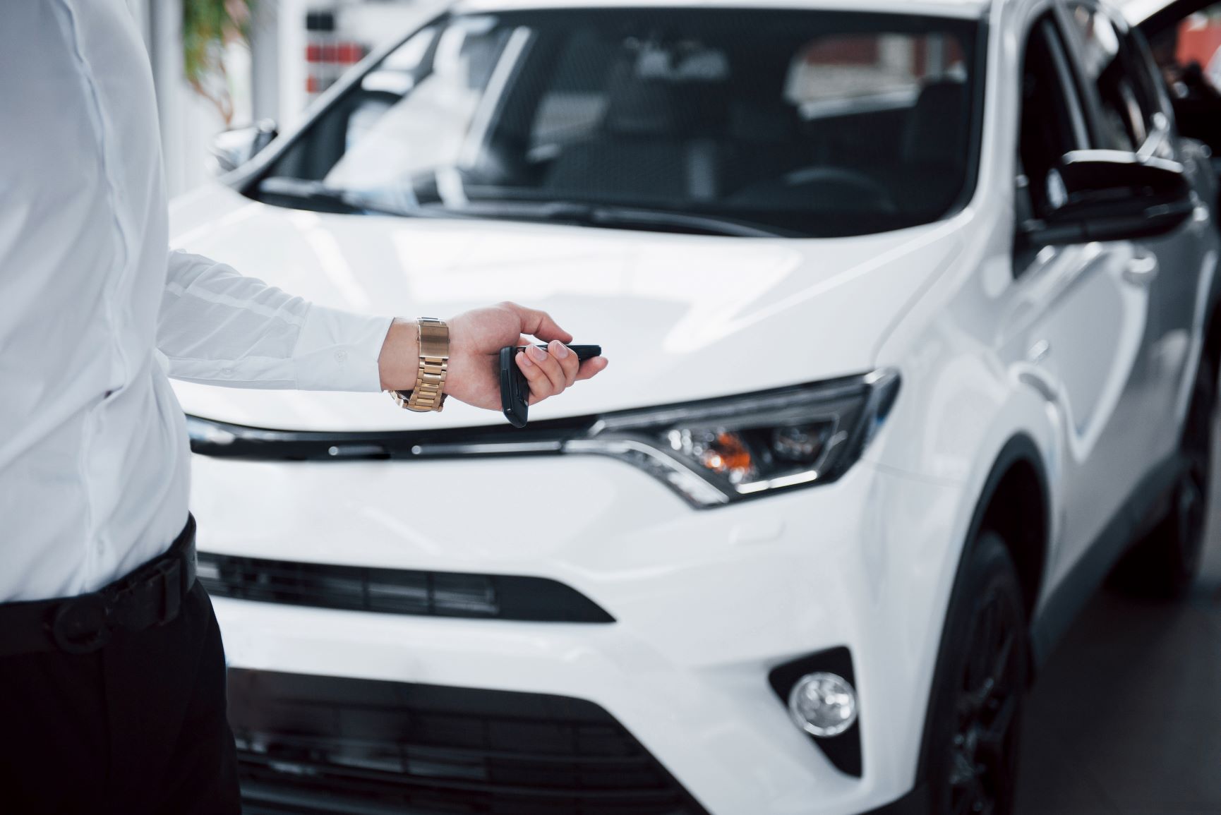 person hold car key fab in front of toyota car
