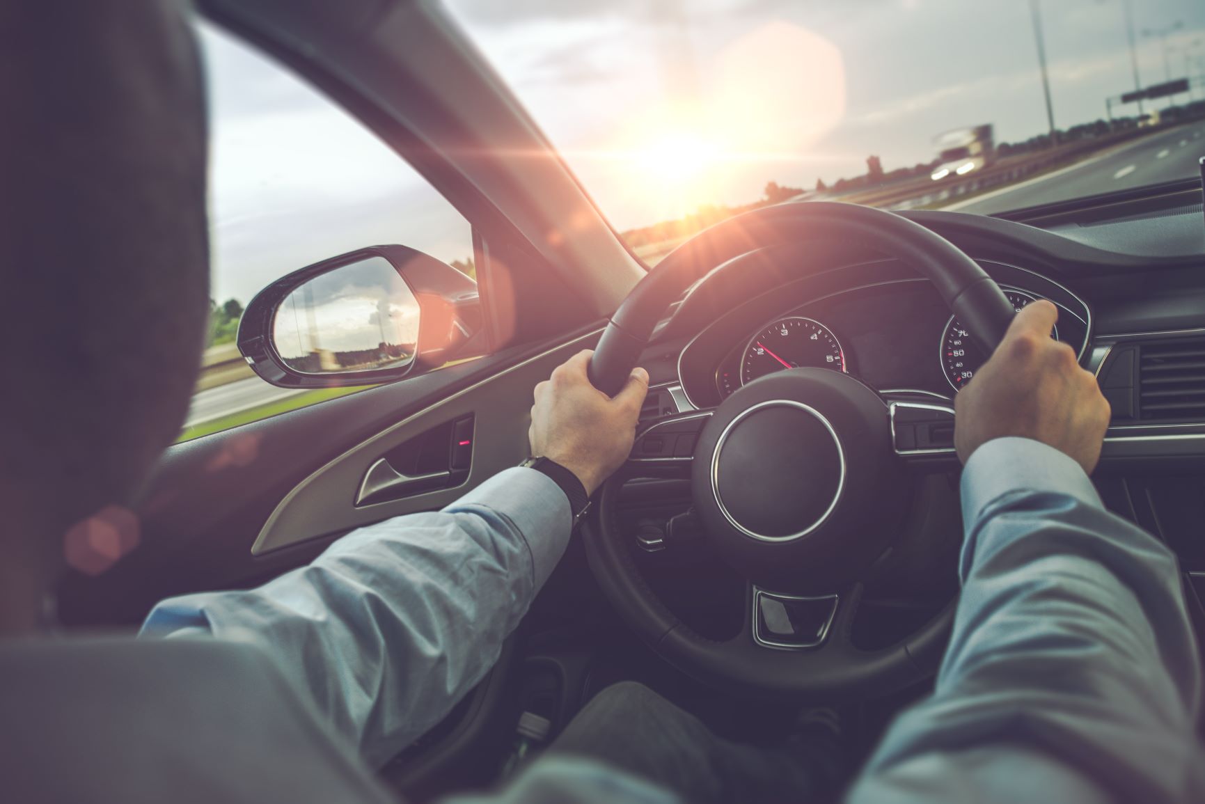 person driving a car at sunset