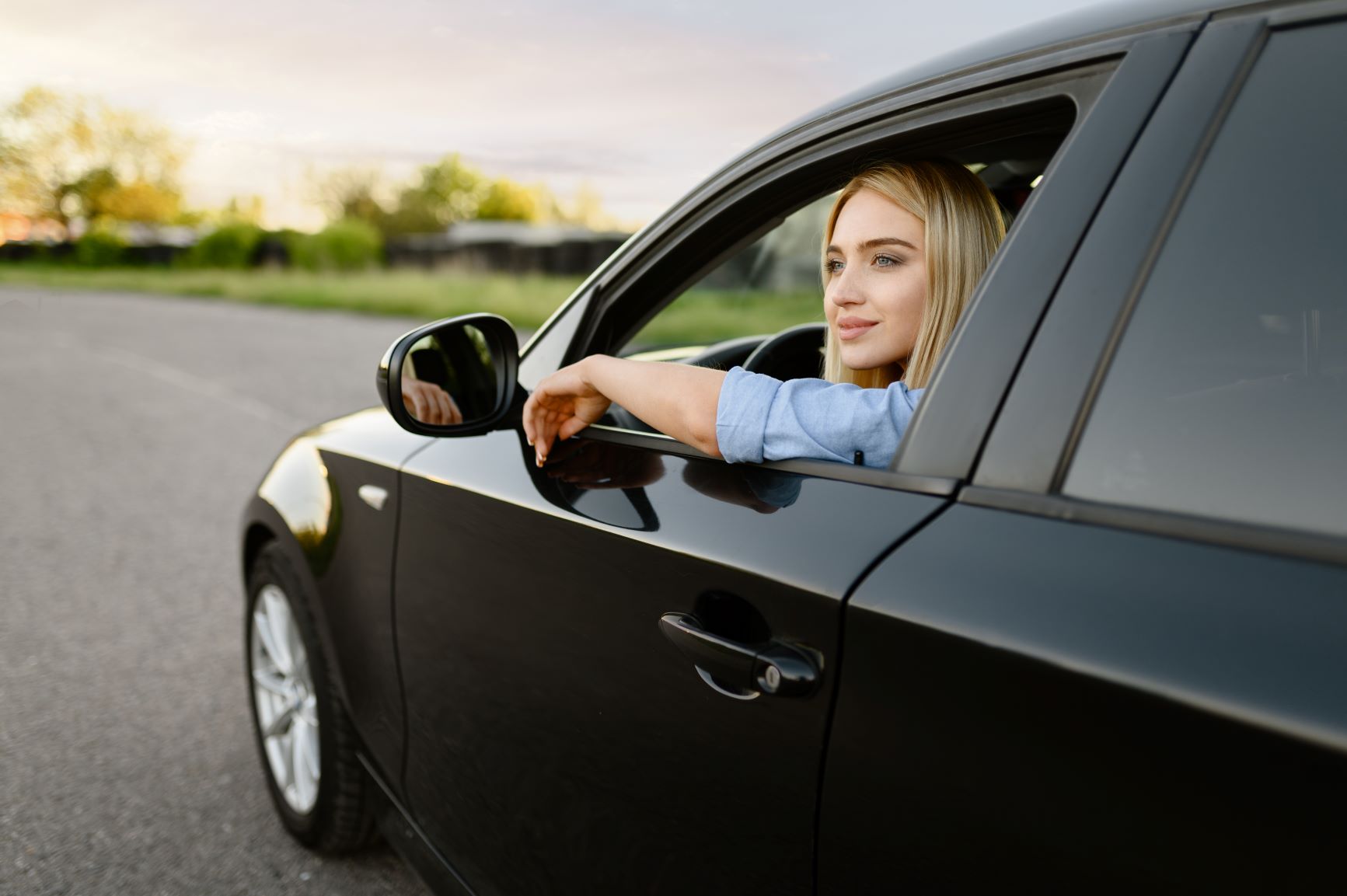 blonde woman looking outside of her car