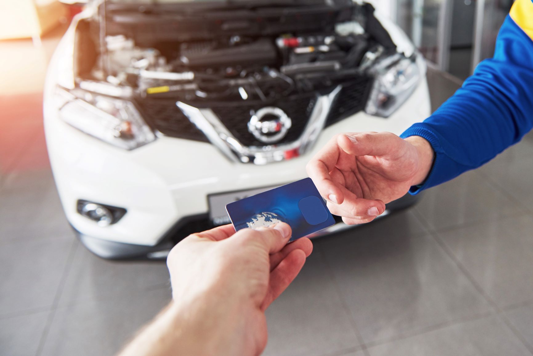 handing a credit card to a mechanic in front of car