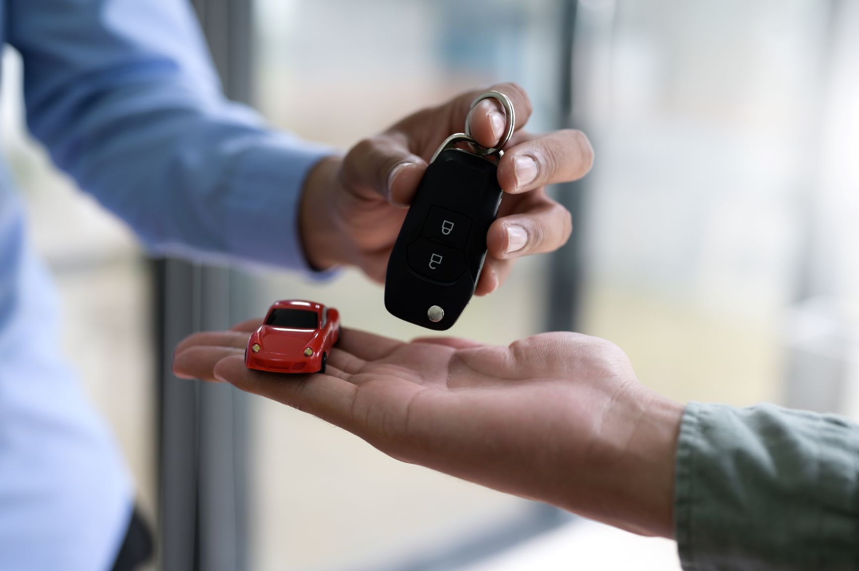 car keys and red toy car with hands in shot