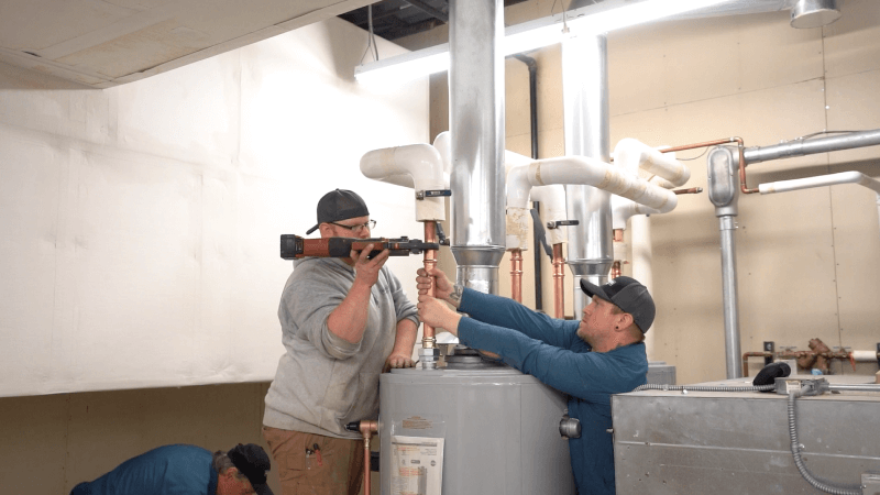 Technicians working on a commercial water heater.