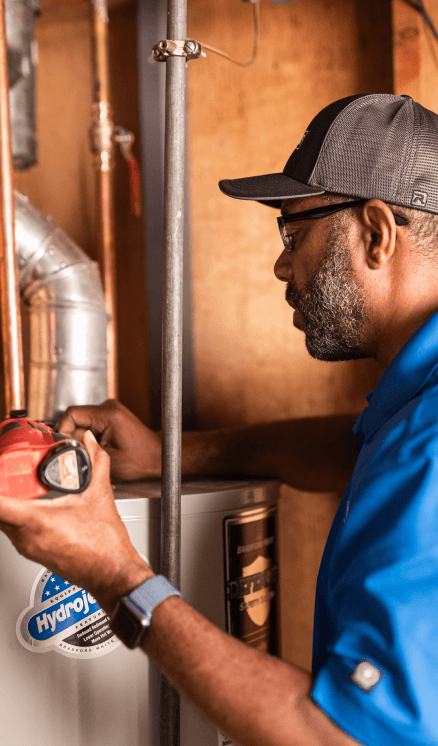 A technician works on a conventional water heater.