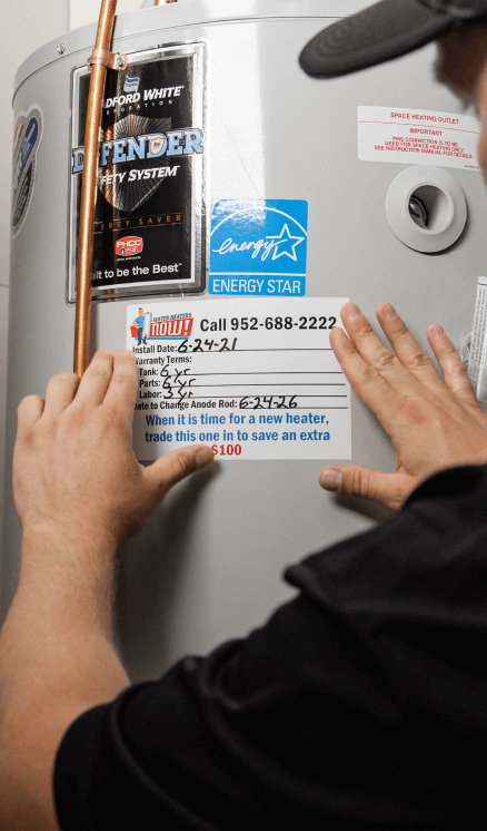 A technician putting a warranty sticker on a water heater.