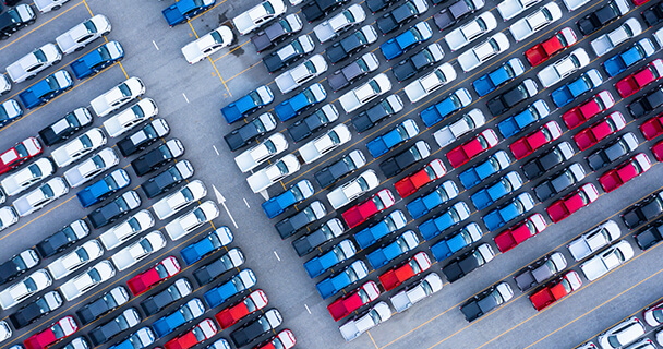 Fifteen rows of trucks of the same model but in different colors parked in a lot.