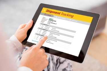 Woman holding a tablet with a "Shipment Tracking" software