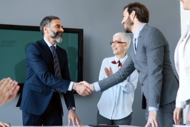 Businessmen handshaking and people applauding