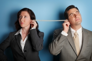 Woman and Man looking at opposite sides both holding a side of a telephone chord.