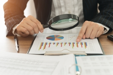 Man looking at graphics with a magnifying glass
