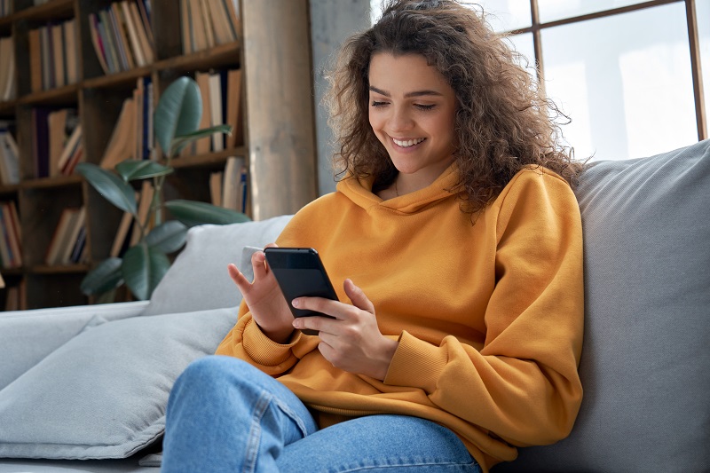 happy woman using social media on her phone at home