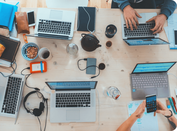 Top down image of a work place, with laptops, phones, and audio equipment.