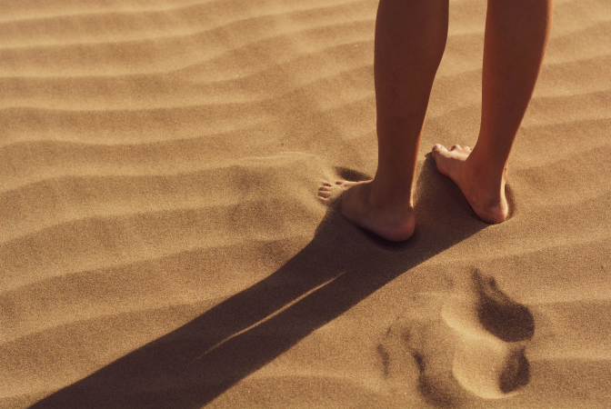 A human leaving footprints behind in the sand