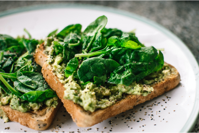 Avocado toast topped with spinach on plate