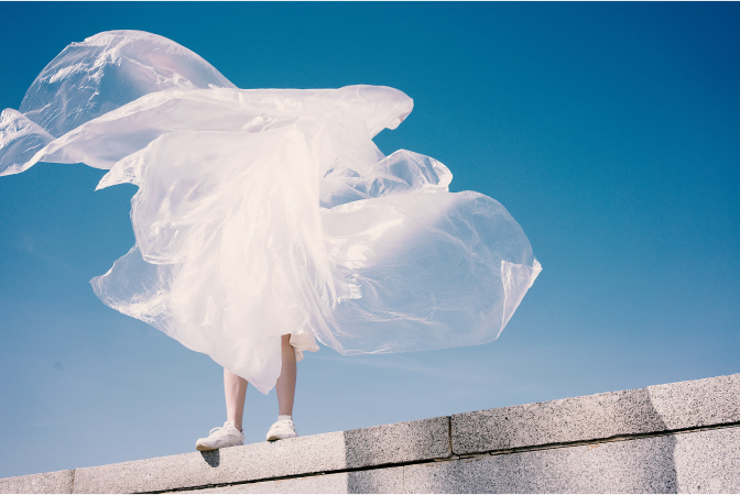 Person holding a large sheet of plastic tarp as the wind blows